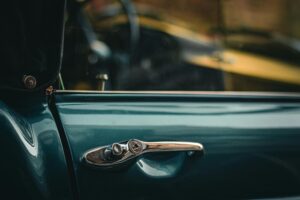 Detailed shot of a metallic blue vintage car door handle with subtle reflections.